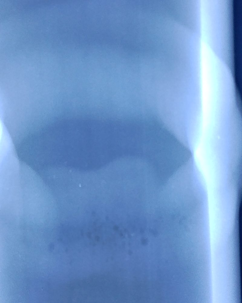 Radiografia do corpo de prova de tubo de 2 polegadas: a solda circunferencial aparece como faixa clara elíptica no filme azul